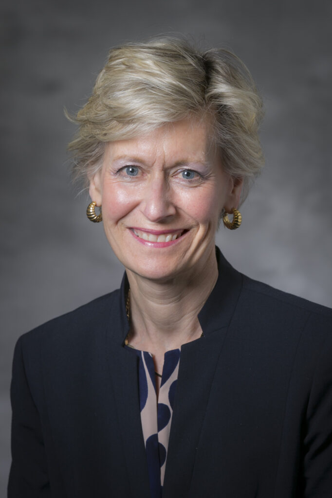 Robin Rasor wearing a black blazer smiles at the camera for an official Duke headshot.