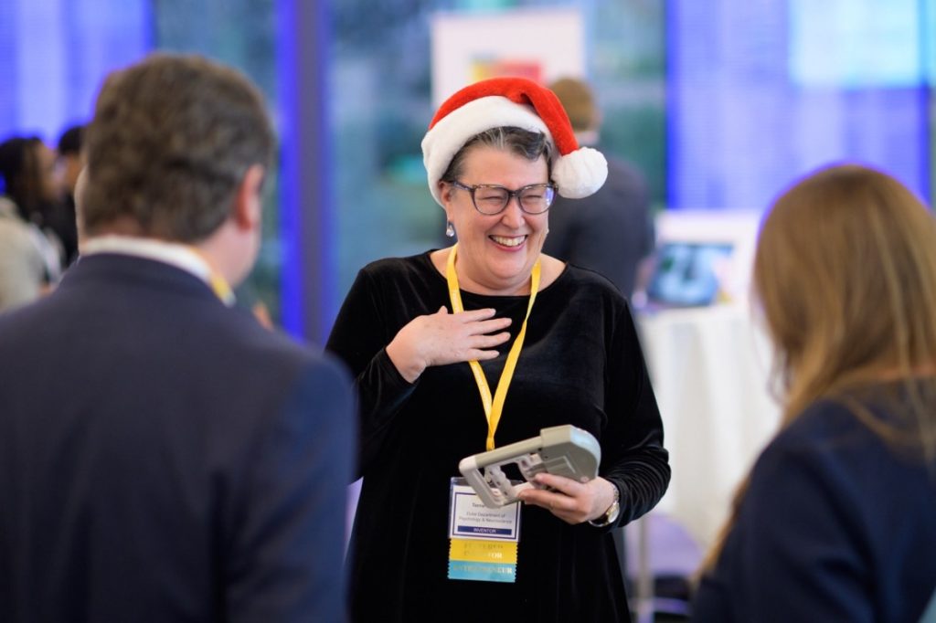 Terrie Moffitt enjoys a laugh with colleagues and attendees while holding a grip strength test device, one of the factors her team tracks to better diagnose age.