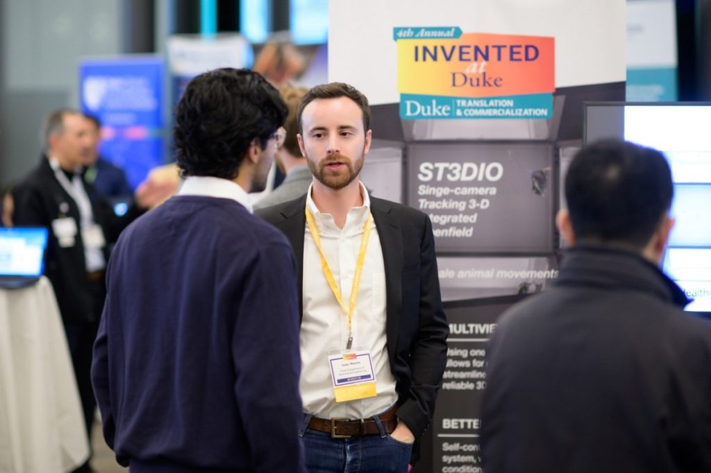 Isaac Weaver, center, explains ST3DIO, a multi-angle, single-camera animal behavior arena, to an attendee.