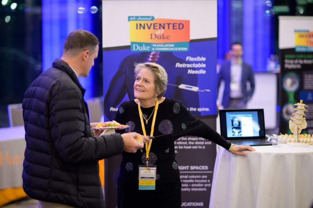 Linda Gray Leithe, holding her flexible retractable needle, chats with an attendee.