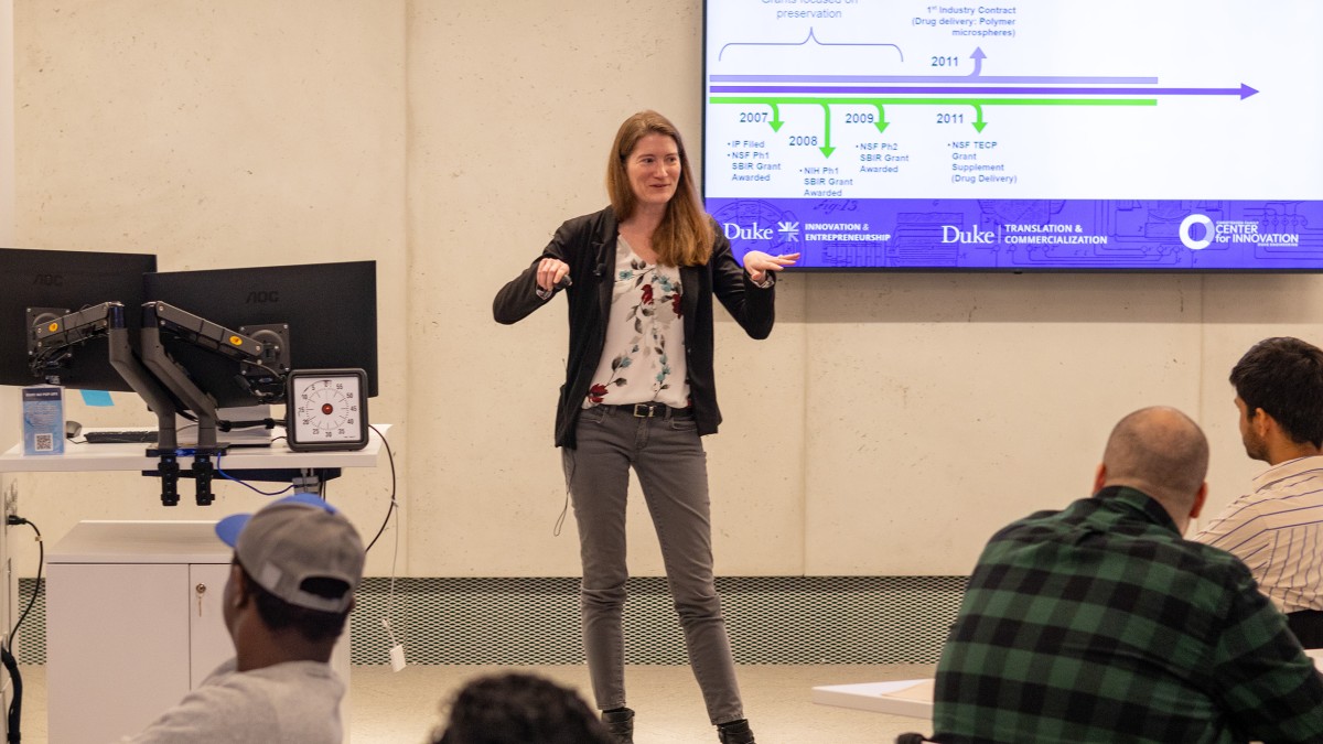 Bitterfield stands in front of a room with a presentation screen behind her, delivering a point to a group of professional students seated in front of her.